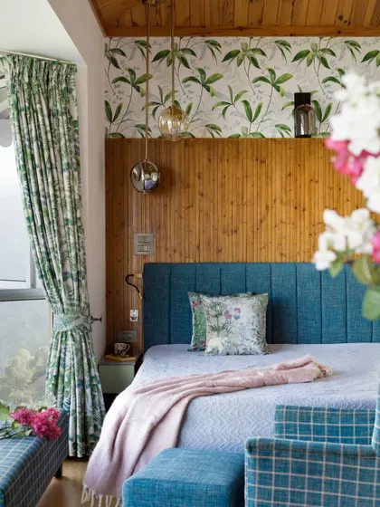 Details in the master bedroom, where floral fabrics and a soft pink throw add a touch of softness to the wood and blue palette. The pendant lights cast a warm glow, perfect for unwinding at day's end.