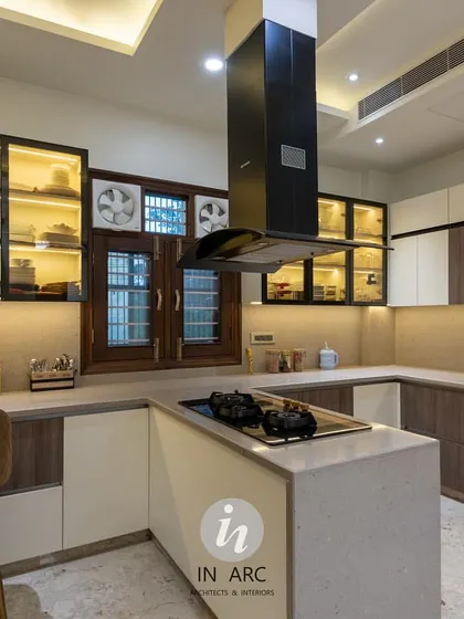 This angle highlights the U-shaped counter layout, providing ample workspace. The combination of wood-grain and white laminates with glass-front upper cabinets creates a balanced, modern look.