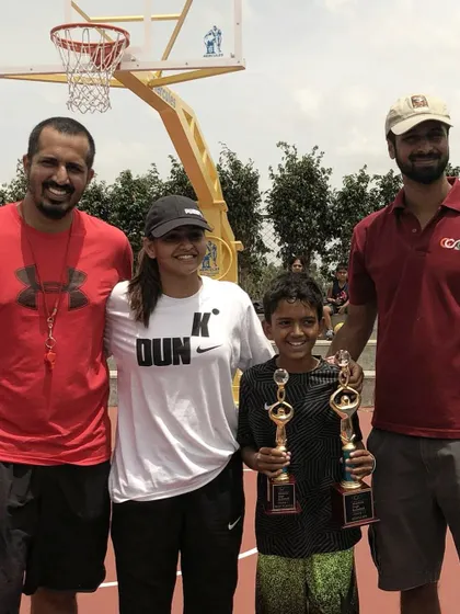 A throwback to our early days on an outdoor court. A young player proudly holds his trophies, a reminder of how far we've come.