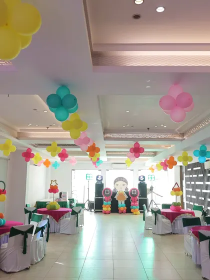 The indoor setup for the 'Squid Fiesta' party, showing the themed table settings, ceiling balloon decorations, and the main stage area. The entire room was transformed to fit the playful and colorful theme.