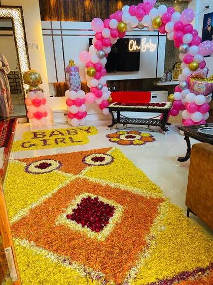An elaborate flower rangoli and 'BABY GIRL' text made from petals, part of a grand home welcome decoration.