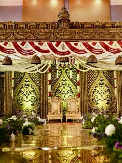 An opulent mandap design featuring antique-gold finished pillars and intricate backdrops, creating a regal atmosphere for a traditional South Indian wedding.