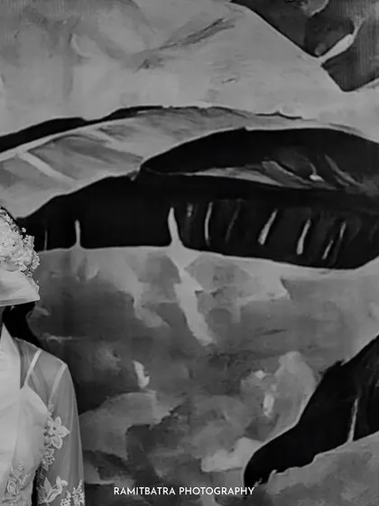 An artistic black and white shot of the bride holding her bouquet in front of her face, against a painted mural.