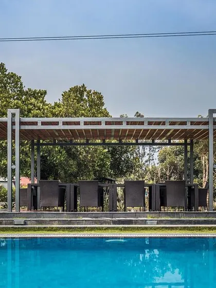 A view of the dining pavilion from across the swimming pool, showing how the leisure areas are interconnected within the landscape design.