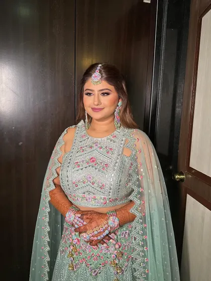 Riddhi looks absolutely beautiful and ready for her mehendi ceremony. The makeup is fresh and bright, perfect for a daytime event.