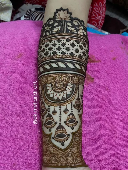 This arm design features beautiful hanging jhumka or bell motifs, a classic element in bridal mehndi.