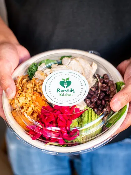 A healthy takeaway bowl held by a customer. This adds a human touch and shows the product in a real-world context.