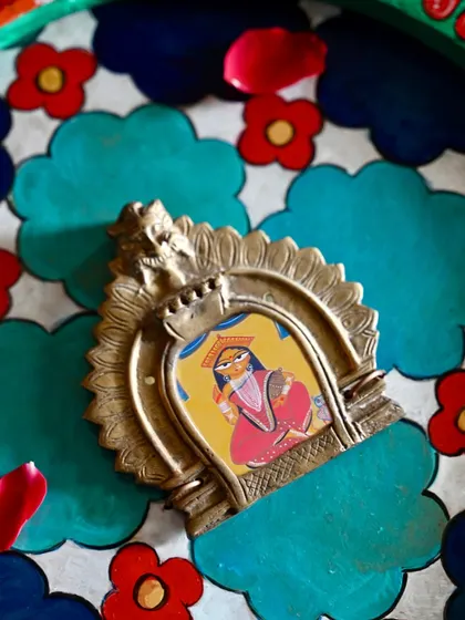 A detail shot of the vintage Prabhavali at the center of the Laxmi frame. The hand-painted image of the goddess is nestled within this salvaged brass halo, creating a focal point of divine energy.