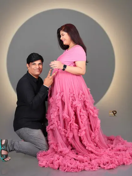 Playful and full of joy. This shot captures the couple's happiness as they await their new arrival. The flowing pink gown adds a touch of romance and fun to the portrait.