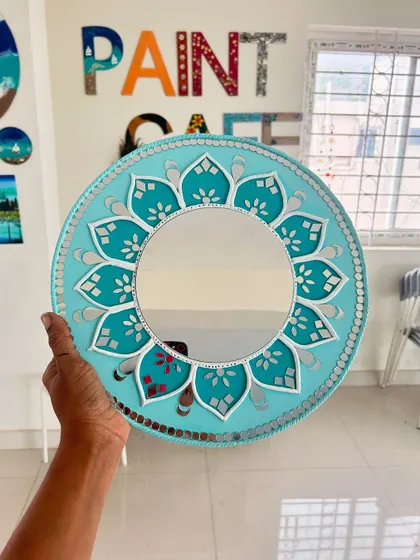 A beautiful mirror art piece, which uses similar techniques to Lippan art. This one features a central mirror with a floral-patterned border.