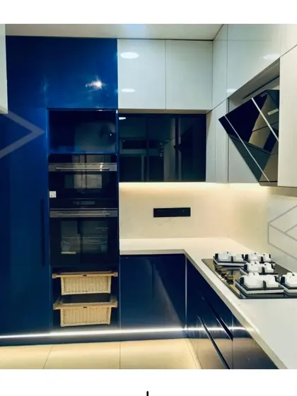 These images provide multiple angles of the stunning blue and white modular kitchen, showing details like the built-in oven tower, the fluted cabinet finish, and the overall clean and spacious layout.