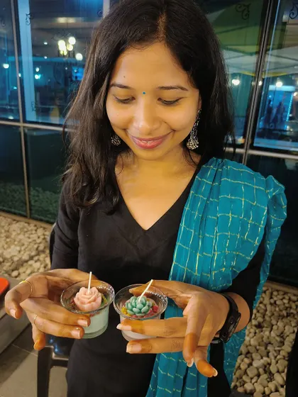 A participant proudly shows off the two beautiful succulent-themed candles she made at our live candle making booth.