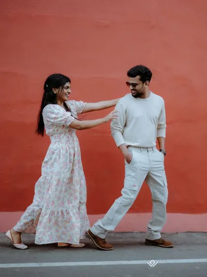 A playful and dynamic shot against a bold red wall, showing how we can use simple urban backdrops for vibrant pre-wedding photos.