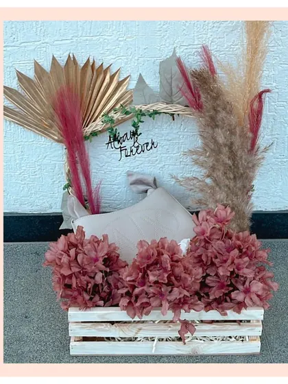 A chic and modern wooden crate hamper with a bohemian vibe. It features dried flowers, pampas grass, and a 'Happy Forever' sign, ideal for an anniversary or wedding gift.