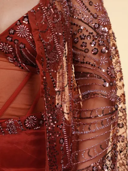 A close-up of the intricate embroidery on the sheer jacket of the rust-colored corset set. The craftsmanship is just incredible.