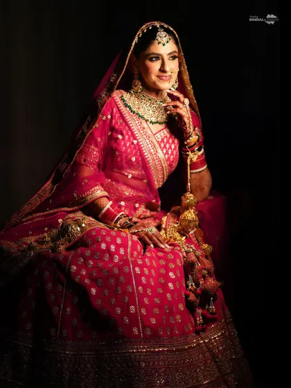 A regal, seated portrait of the bride. The dark background and dramatic lighting make her and her opulent outfit the undeniable center of attention.