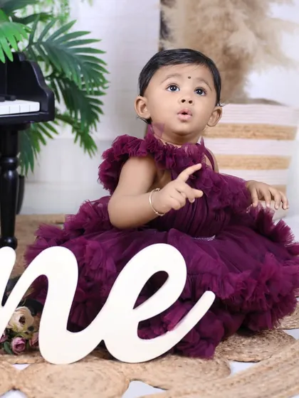 A close-up on the birthday girl in her gorgeous ruffled dress, with the "one" sign prominently featured. Her curious expression is absolutely priceless.