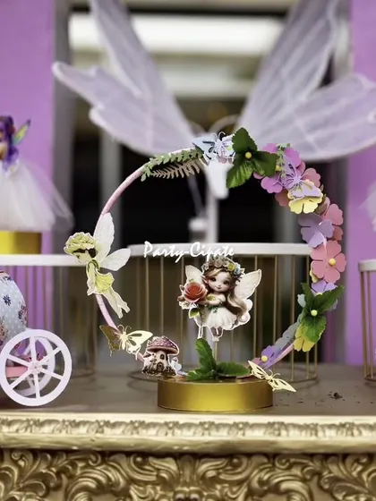 It's all about the tiny, magical details. This centerpiece for a fairy-themed party includes handcrafted fairy figurines, a miniature carriage, and a floral hoop, all designed to create a sense of wonder.
