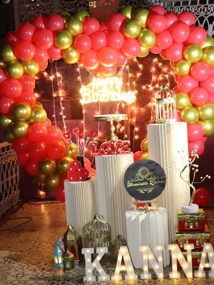 A romantic birthday setup with a red and gold heart-shaped balloon arch and marquee letters.