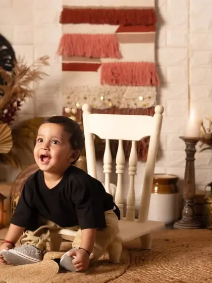This little one is full of excitement, trying to climb onto a small chair during his first birthday shoot.