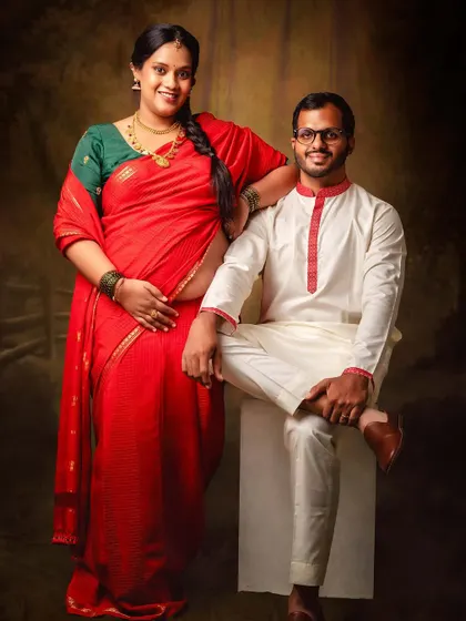 A beautiful portrait of a couple celebrating their journey to parenthood. The traditional red saree and white kurta create a classic and elegant look.