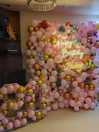 A different angle of the at-home 20th birthday balloon wall, showcasing the mix of pink and gold balloons with floral accents.