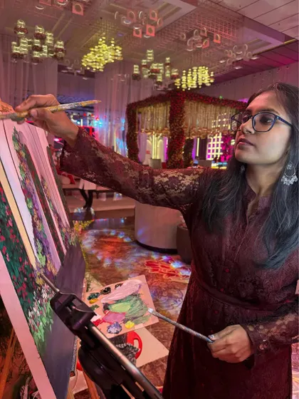 Deep in focus during a live painting session. You can see the grand wedding mandap in the background, which I am translating onto the canvas while the event unfolds around me.