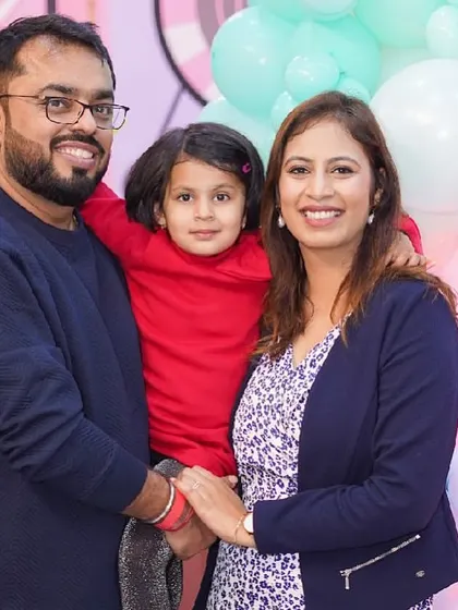 A sweet family photo in front of a Peppa Pig themed birthday cake and backdrop.