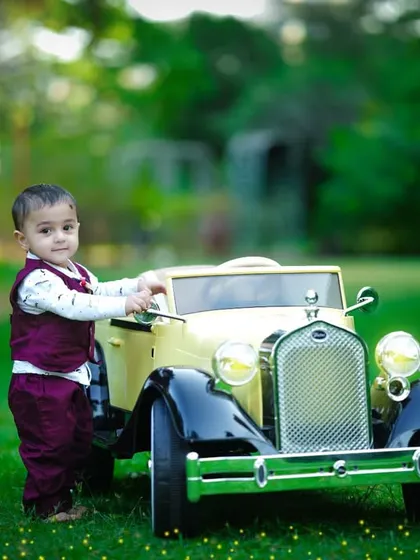 A candid moment as the toddler interacts with his toy car in the beautiful green surroundings.