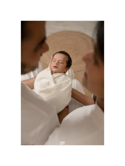A unique perspective, looking down as parents cradle their sleeping newborn. This intimate angle highlights the baby's peacefulness and the parents' protective love.