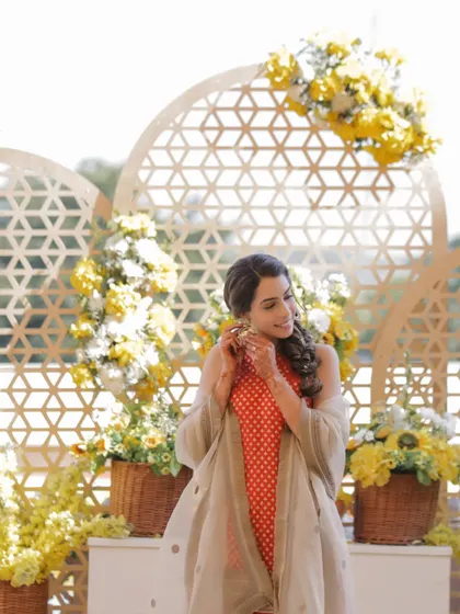 The bride posing against a beautiful yellow floral backdrop at her Haldi.