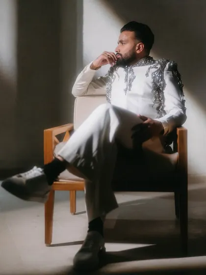 The groom, looking thoughtful and dapper in a moment of quiet reflection. The dramatic side lighting highlights the texture and detail of his stylish outfit.