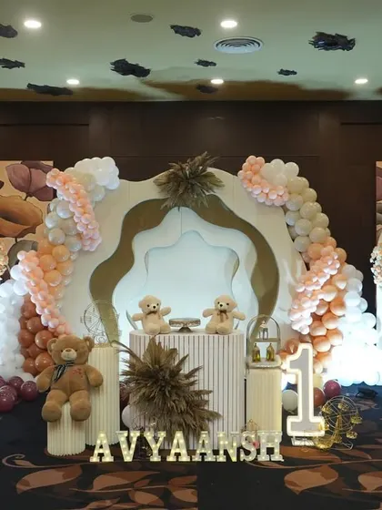 A cozy and cute teddy bear themed birthday setup. The decor uses neutral and earthy tones, with multiple teddy bears, custom backdrops, and a light-up name sign creating a warm atmosphere.