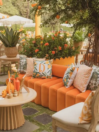 A curved orange velvet sofa is decorated with custom-printed cushions, creating a chic and comfortable lounge spot.