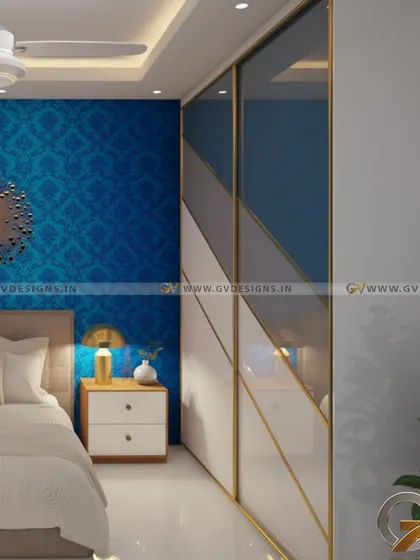This custom Aristo sliding wardrobe features a unique design with colored glass panels arranged in a bold, diagonal pattern. The gold frame adds a touch of luxury, while the blue accent wall with damask wallpaper creates a rich, vibrant backdrop.