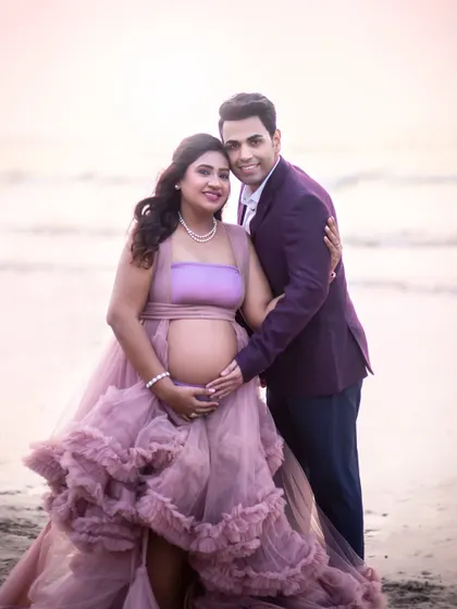 A classic pose showing off the baby bump, with both parents looking radiant and happy. The soft light of the beach at sunset is incredibly flattering.