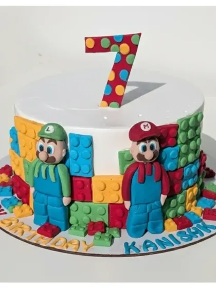 A creative crossover of Super Mario and LEGO for a 7th birthday. This soft eggless truffle cake features handmade fondant figures of Mario and Luigi surrounded by colorful, edible bricks.