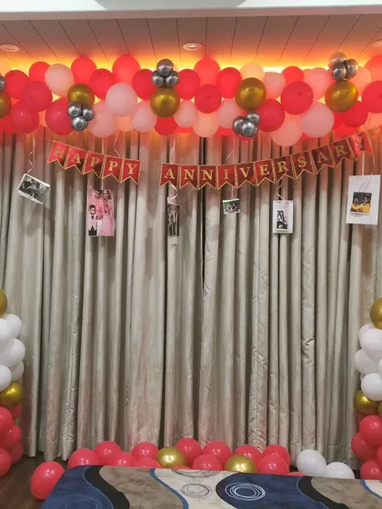 A lovely anniversary decoration in front of a window. We created a balloon garland at the top, two balloon pillars, and hung photos from the garland to add a personal touch.