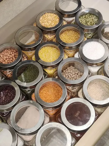 This drawer is an organizer's dream, filled with Tero-branded glass jars with clear lids, each containing different dals and pulses. It’s a perfect example of a functional and beautiful system.