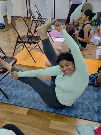 A student smiling through a challenging hip-opening pose during our Sunday workshop. The joy is in the effort.