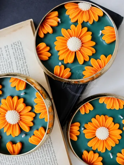 Another look at the contrast between the tangerine orange daisies and the rich green wax. The little pearl-like wax drops add an extra touch of elegance.