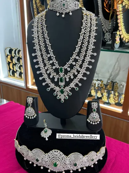 A complete bridal AD set, featuring a multi-layered haram, choker, hip belt, and maang tikka. This set with green stones provides a grand and cohesive look.