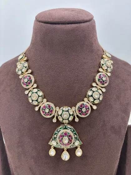 A unique necklace with a pendant featuring green and red Meenakari work, perfect for adding a pop of color.