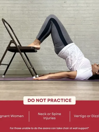 We teach safe modifications for every pose. This image shows a chair-supported variation of Sarvangasana, making the pose accessible to all.