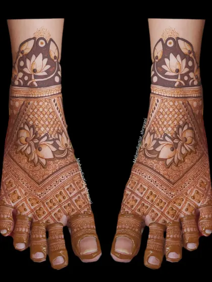 A symmetrical and intricate foot mehendi design. The pattern uses jaali (net) work and floral motifs to create a rich and detailed look.