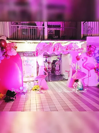 The entrance to the flamingo party, featuring a custom arch and flamingo cutouts, all lit up in shades of pink and purple.