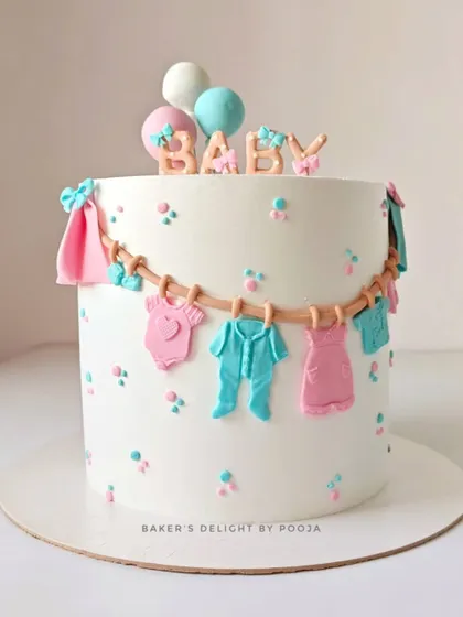 A lovely baby shower cake with a clothesline of tiny, handcrafted fondant baby clothes in pink and blue. This design is perfect for a gender-neutral celebration, topped with the word "BABY" and cute balloons.