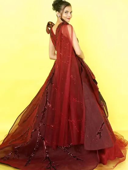 The back view of the maroon ballgown reveals a delicate, flowing cape, adding another layer of drama and elegance to this incredible outfit.