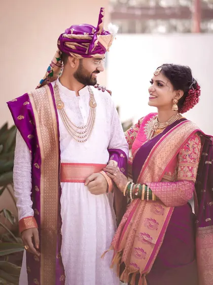 A classic wedding portrait where the couple stands together, looking at each other with love. Their elegant purple and pink outfits are beautifully captured.