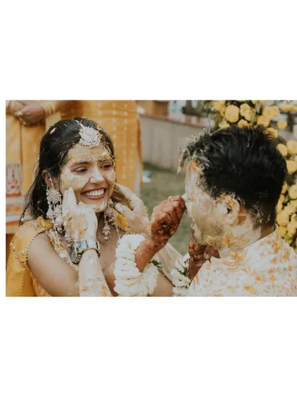 A playful and intimate moment between Nikita and Akash during their Haldi, as they lovingly apply turmeric to each other's faces.
